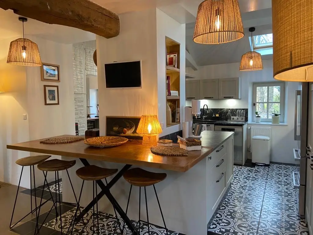 Cuisine rustique avec façades bois massif, crédence verte et sol carrelage en damier